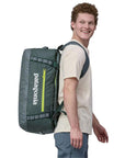 Patagonia Black Hole Duffel Bag 55L (Nouveau Green) man wearing duffel bag
